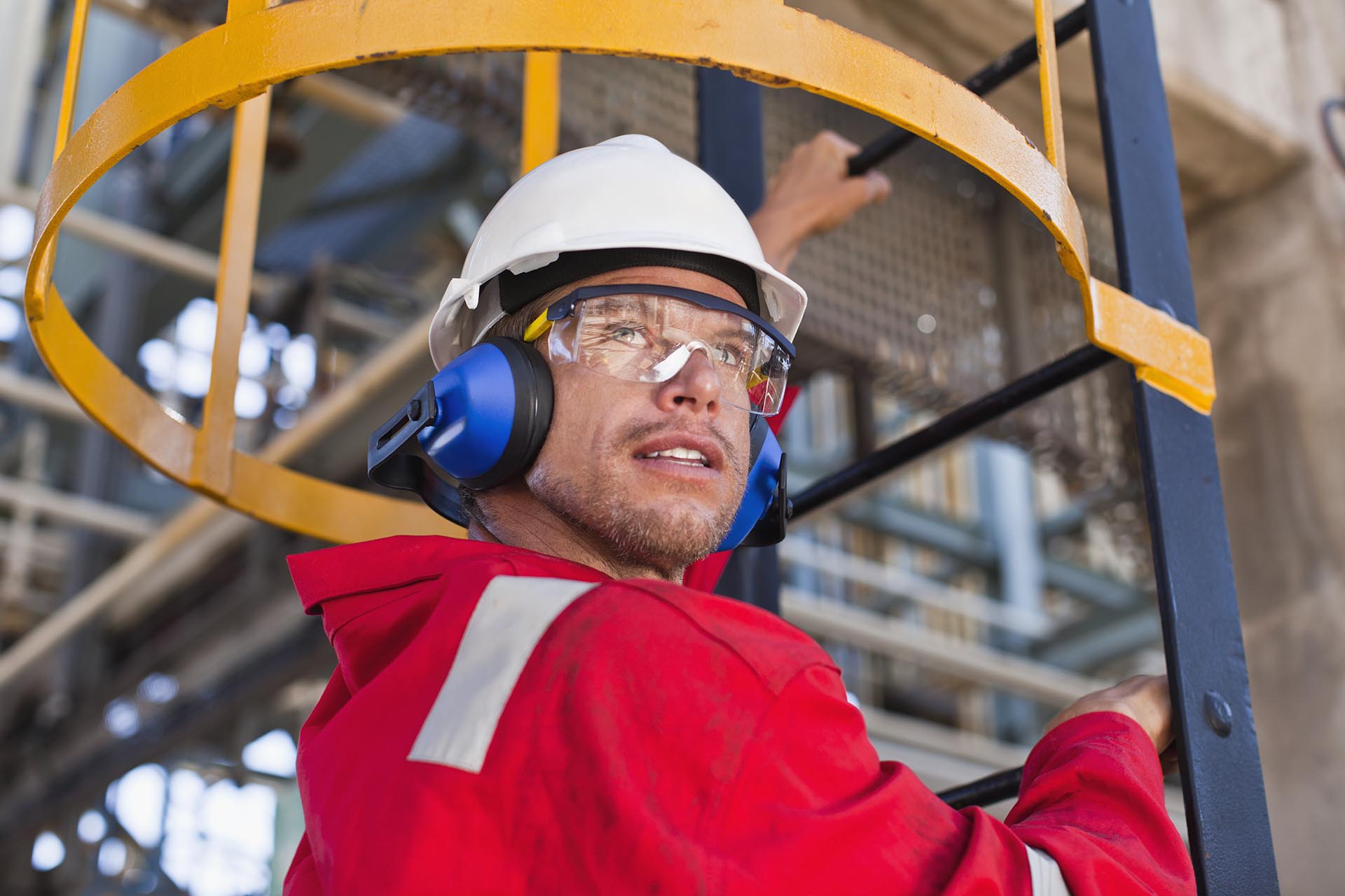 Worker climbing ladder at oil refinery